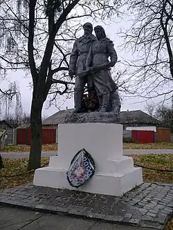 Statue of a man and a woman in winter clothing, the woman holding a rifle
