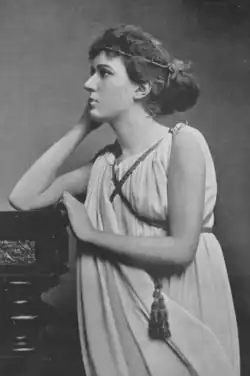 A young white woman wearing classical Greek-inspired dress, photographed almost in profile