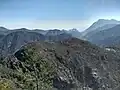 Mt. Tavagnone and its pastures of the former Battista Corsetti "Prandini" Fund, Dos di Sas and the Vein Pass on the far right, and ascending the ridge on the left three mountains, Mt. Gas respectively of 1,128 m., and two other unknown ones of 1,143 m., 1,067 m., while in the background the artificial lake of Valvestino, Mt. Pizzocolo, Mt. Castello and Lake Garda with the Sirmione peninsula.