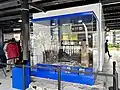 A glass box containing remnants from the arson incident during the widespread protests in late August 2025, which includes a scorched TV set, turnstile and wall fan.