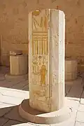 The lower section of a column, still standing, with inscriptions and the image of a person