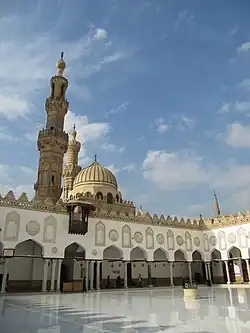 View inside the main courtyard of al-Azhar Mosque. A pointed dome and a minaret tower rise above.