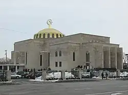 A large grayish stone building, topped with a golden dome.