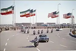 Motorcade carrying U.S. President Richard Nixon during his trip to Tehran, Iran in 30–31 May 1972, with large Iranian and U.S. flags in the background