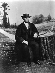 A black-and-white portrait of McKiernan seated on a log
