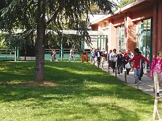 Children walking along a modern, wooden building