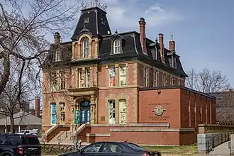 Three-storey red-brick building with a black roof and white trim around the windows