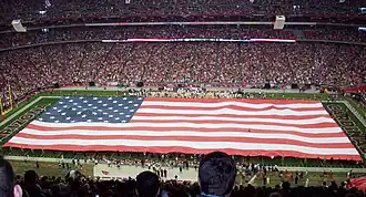 A large flag displayed during the singing of The Star-Spangled Banner prior to the start of an NFL game.