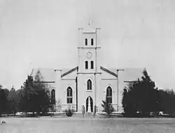 Historical black-and-white photograph of the Dutch Reformed Church in Boshof, showing a large building with twin towers and surrounding trees