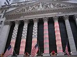 The columns of the NYSE lit up for Christmas, with the American flag being projected onto the colonnade