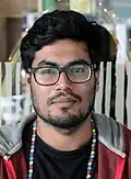An Asian man wearing glasses looking in front of camera.