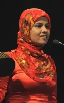 Sheela holding an award and giving a speech
