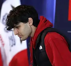 Nalin Haley photographed from the side, wearing a red jumper and grey parka