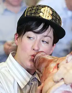 Headshot of Pomeroy kissing a deceased pig's head whilst wearing a baseball hat