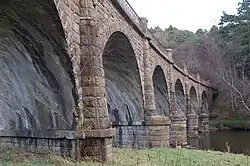 Close-up of a land-based pier with the soffit of one of the arches in the foreground. In the background other arches span the river as the viaduct curves gently to the right