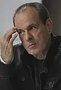A man is wearing a black jacket and is facing left