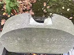 A top-down view of the gravestone showing damage to the center where an Orthodox cross had been affixed
