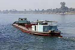A cargo boat, empty, in a wide river