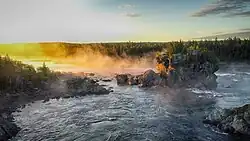 the image shows a large rock standing in the river Exploits in the early morning mist