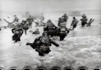 A blurry picture of American men moving through the water to the beach.