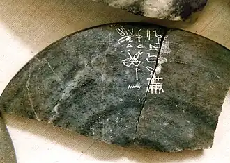 Fragment of a dark-grey stone bowl inscribed with light-coloured hieroglyphs