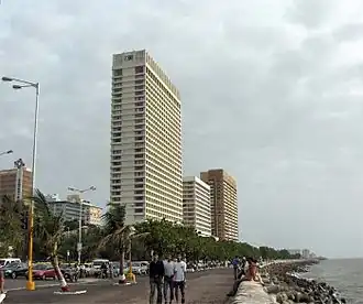 A color photograph of a tall white building located on a seafront promenade
