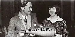 Black and white publicity photograph showing a film director and actress on a movie set