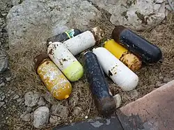 A pile of rejected and somewhat rusty scuba cylinders lying in a yard