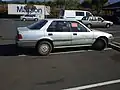 Late 80s Honda Accord with a sticker violation tag for illegal parking.