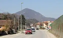 cars driving down the street with a mountain in the background