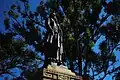Statue of Benito Juárez made in 1894 at Paseo Juárez "El Llano" in the historic centre of Oaxaca. Juárez holds a Mexican flag with one hand and points with the other to the Imperial Crown of Mexico below, representing the republican defeat of the Second Mexican Empire.