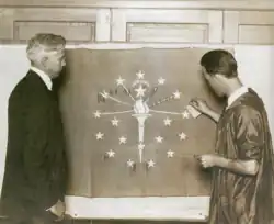 Paul Hadley (left) watches as Ralph Priest, a student at Herron School of Art, applies gold leaf to his flag, 1917.[18]