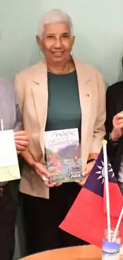 Peggy Carr holds a book behind a Taiwanese flag