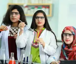 Female pharmacy students conducting a practical laboratory session while wearing safety goggles.