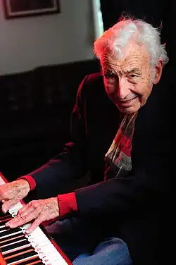A color photograph of producer Phillip Springer in a recording studio on the piano.