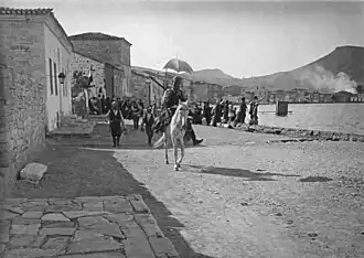 Çetes parading with loot in Phocaea (modern-day Foça, Turkey) on 13 June 1914. In the background are Greek refugees and burning buildings.