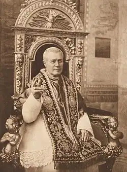 The Pope, seated on an ornate throne in ceremonial vestments with a papal tiara, blessing with his right hand. Richly embroidered liturgical garments.
