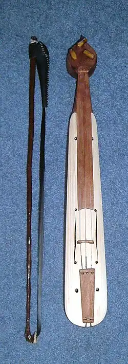 A bottle-shaped wooden string instrument next to a bow