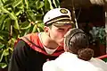 A man in a sailor costume kisses a woman in a white dress during a performance