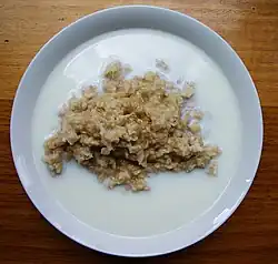 Cooked grain porridge with milk pooling around the edges of the bowl