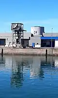 Ice tower: ice is produced in the cylindrical tower, conveyed to the gantry, lifted by a conveyor belt, and loaded onto fishing boats.
