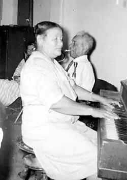 Pierce playing the piano with husband De De Pierce on trumpet in the background, 1949
