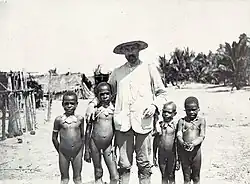 Four small Papuan boys posing naked with white male missionary, 1908
