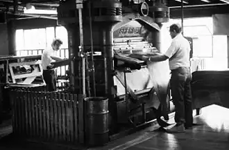 Two men pressing the leather near the end of the tanning process, October 1975