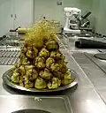 A large stack of profiteroles covered in caramel sauce