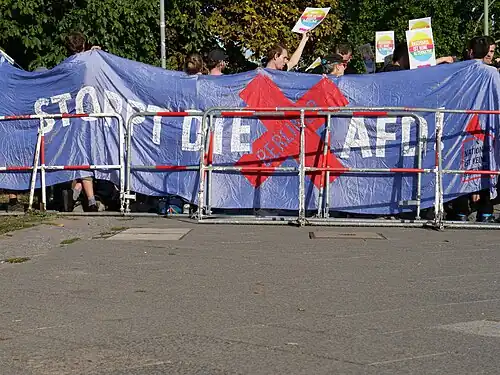 NIKA logo in the corner of a banner saying in German: Stoppt die Berliner AfD, lit. 'Stop the AfD Berlin', in Spandau in 2018 [k]