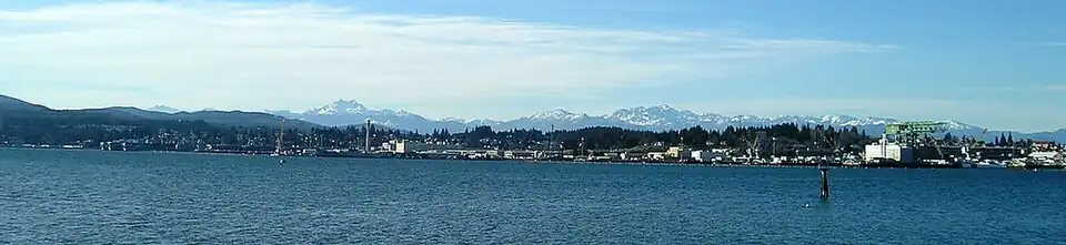 Puget Sound Naval Shipyard, as seen from across the water in Port Orchard. The mothballed ships are on the left, and the hammerhead crane is on the right.