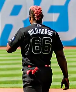 Yasiel Puig, facing away, wearing a black Cleveland uniform with "Wild Horse" written on the back.