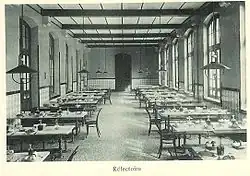 Photograph of the lycée's dining hall: aligned tables and chairs.