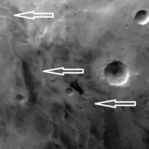 Ridges, believed to be eskers of the Dorsa Argentea Formation, as seen by Mars Global Surveyor wide angle MOC. White arrows point to the ridges.